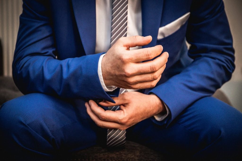Close-up of a businessman adjusting his blue suit and necktie.
